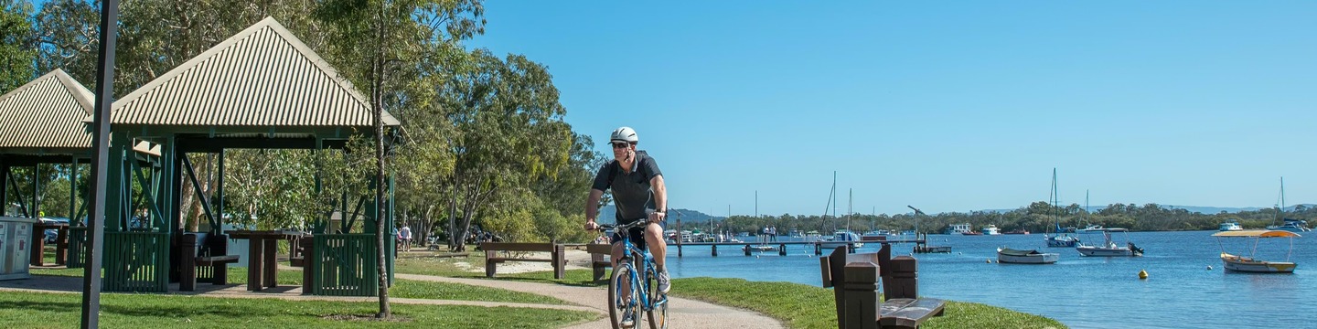 Male on a bicycle cycles on the Noosaville foreshore pathway