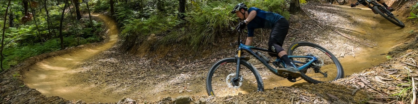 Male on a mountain bike goes around a sharp mountain trail turn