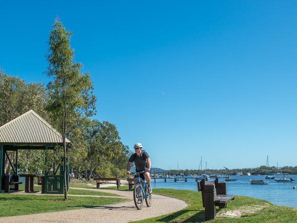Male on a bicycle cycles on the Noosaville foreshore pathway
